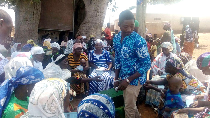 The Communications and Advocacy Officer of RAINS, Mr Andy Clement Mumuni, helping VSLA members at Nanton-Kurugu to share their contributions